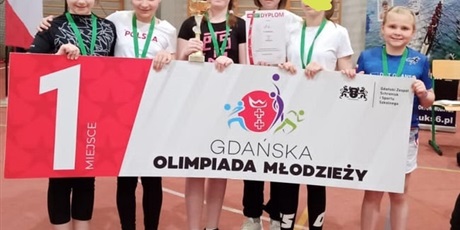 Powiększ grafikę: Nagrodzone uczennice z medalami  trzymają transparent  promujący zawody Gdańskiej Olimpiady Młodzieży