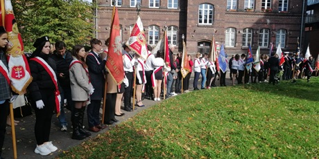 Powiększ grafikę: Uczniowie ze sztandarami stoją na chodniku