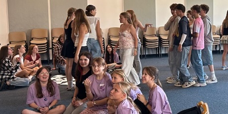 Powiększ grafikę: Uczniowie na auli szkolnej siedzą na podłodze