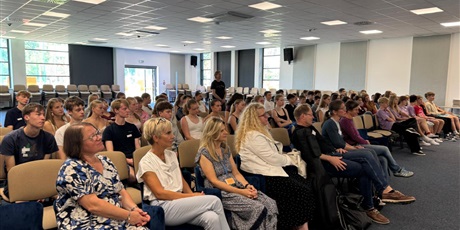 Powiększ grafikę: Nauczyciele, uczniowie i goście siedzą na auli i oglądają prezentacje