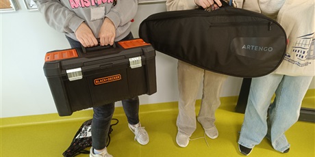 Powiększ grafikę: Uczennice trzymaja w rękach skrzynkę narzędziową i torbę na instrument