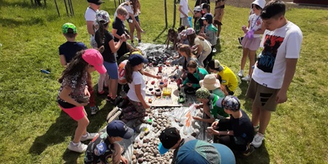 Powiększ grafikę: Warsztaty artystyczne-dzieci maluja na trawie kamienie