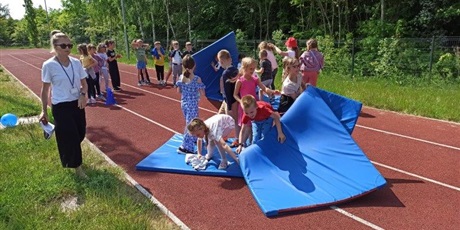 Powiększ grafikę: Zabawa latające dywany. Uczniowie z niebieskimi materacami  na bierzni
