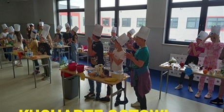 Powiększ grafikę: Kucharze gotowi.Uczniwoe przygotowują się do rywalizacji stojąc przy stołach z czapkami kucharskimi na głowach