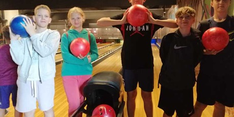 Powiększ grafikę: Pięciu uczniów drużyny reprezentantów ZSP nr 6 na torze bowlingowym Centrum U7 po grze, trzymający kule.