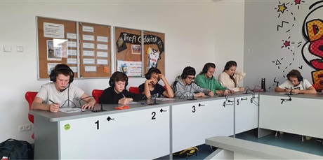 Powiększ grafikę: Uczniowie siedzą w ławkach ze słuchawkami na uszach