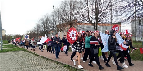 Powiększ grafikę: Uczniowie maszerują z flagami i kotylionami