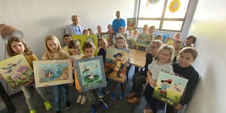 Powiększ grafikę: Dzieci, Dyrektor Piotr Szepelowski, Wicedyrektor Katarzyna Filipska pozują do zdjęcia z obrazami od Seniorów.