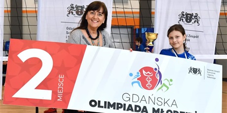 Powiększ grafikę: Uczennica  z Panią dyrektor Iwoną Stankiewicz z pucharem i transparentem, na którym jest informacja o 2 miejscu w turnieju
