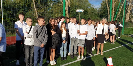 Powiększ grafikę: Uczniowie z wychowawcą stoją na boisku szkolnym