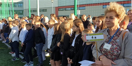 Powiększ grafikę: Uczniowie z wychowawcą stoją na boisku szkolnym