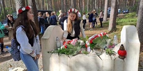 Powiększ grafikę: Uczennice składają kwiaty na grobie