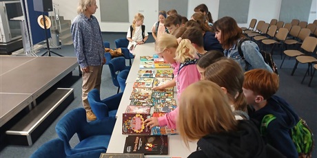 Powiększ grafikę: Uczniowie oglądają książki na stole