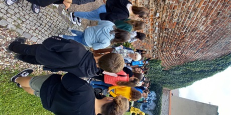 Powiększ grafikę: Uczniowie stoją pod ściana z cegieł z wmurowanymi odciskami dłoni